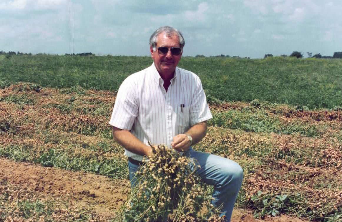 Kelly Seed Robert C. Kelly in peanut field sunglasses white striped shirt lightwashed jeans picking peanuts