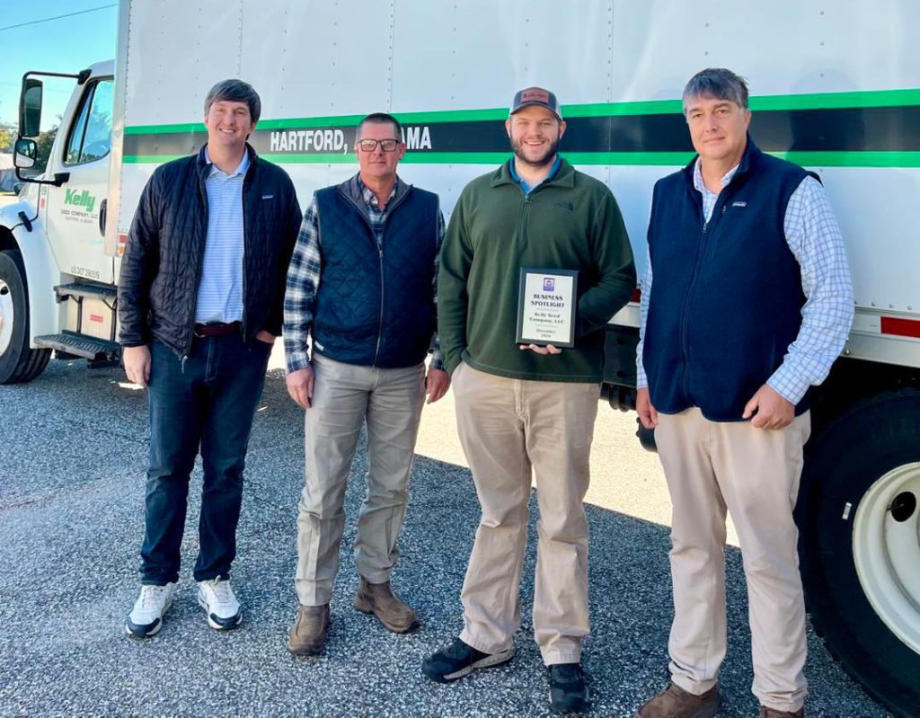 Kelly Seed company group photo in Hartford, Alabama four guys khakis and jeans with small plaque award in front of semi truck